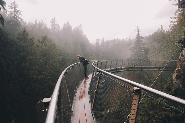 suspended bridge British Columbia Man walking through dense forest on a suspended bridge
