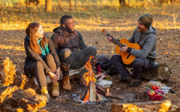 Campfire music Three people enjoying music around a campfire