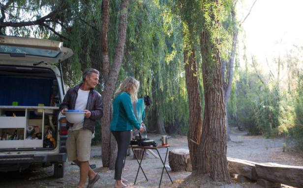 Tree lined campground Two people in a campground making a meal