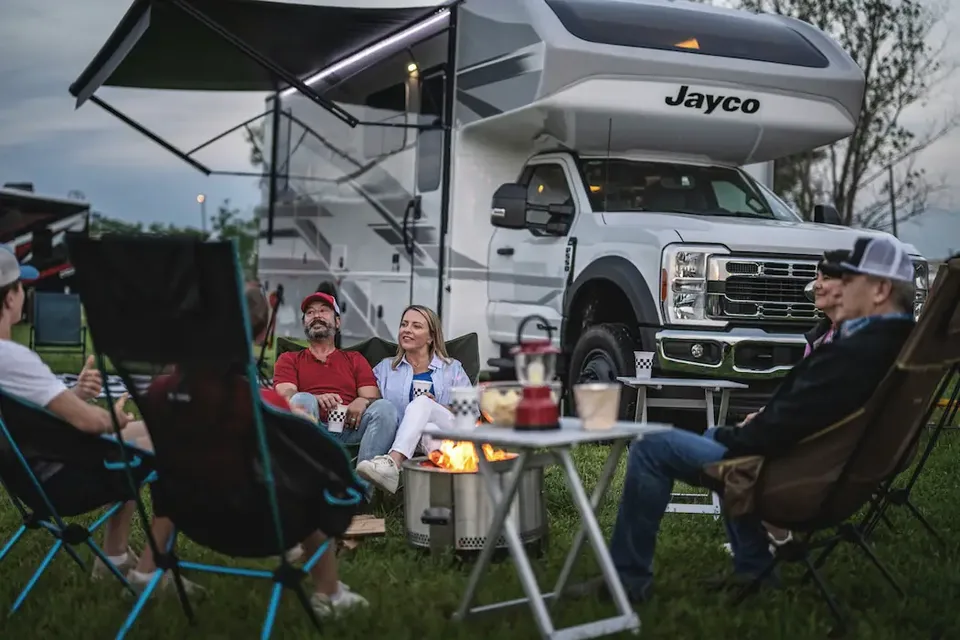 A family enjoying a camping setup with a Jayco RV, with a testimonial praising RVezy for their reliability and comprehensive coverage.